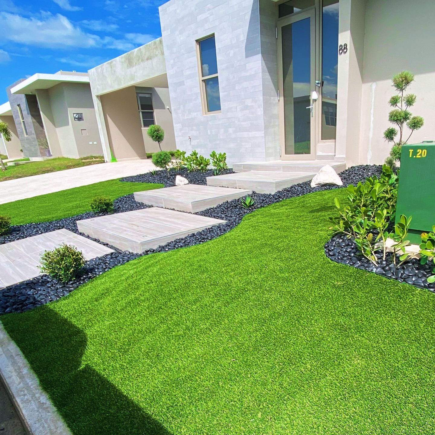 Front yard with synthetic turf and a curved black rock border